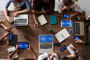 Overhead view of a diverse team in a business meeting using laptops and tablets.